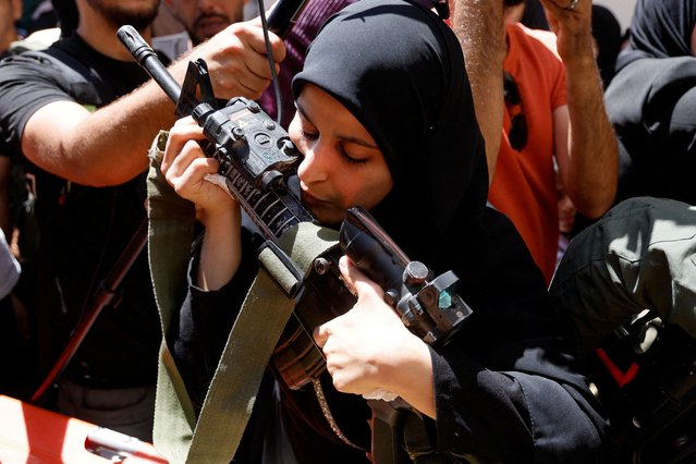 Haneen, sister of Mohammad Shehada who was killed in an Israeli airstrike, kisses his rifle during the funeral of four Palestinians in Nour Shams camp, in Tulkarm, in the Israeli-occupied West Bank on July 3, 2024. (Photo by Raneen Sawafta/Reuters)