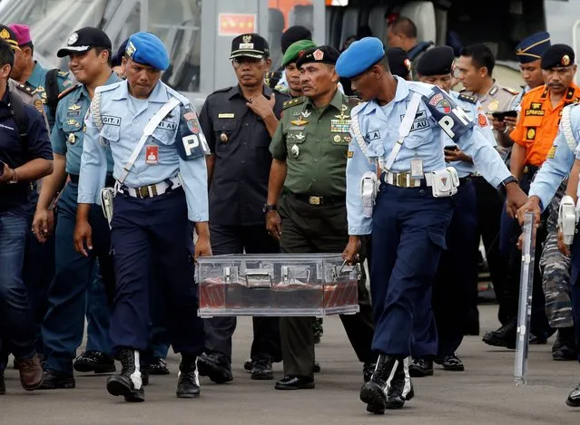 Indonesian air force personnel carry the flight data recorder of the ill-fated AirAsia Flight 8501 that crashed in the Java Sea, at airport  in Pangkalan Bun, Indonesia, Monday, January 12, 2015. Divers retrieved one black box Monday and located the other from the AirAsia plane that crashed more than two weeks ago, a key development that should help investigators unravel what caused the aircraft to plummet into the Java Sea. (Photo by Achmad Ibrahim/AP Photo)