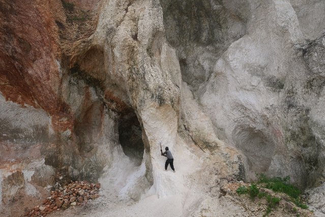 A worker pounds into a wall of rock to make gravel and sand in the Kenscoff neighborhood of Port-au-Prince, Haiti, Friday, October 17, 2025. (Photo by Odelyn Joseph/AP Photo)