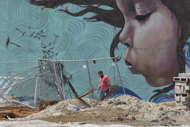 A worker passes by a graffiti on the pylon of the dismantled the “Old Sava bridge” over Sava river, in Belgrade, Serbia, Friday, July 18, 2025. (Photo by Darko Vojinovic/AP Photo)
