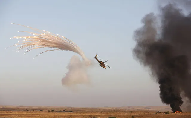 An Israeli Apache helicopter releases flares after it fired at targets (R) during the air force pilots' graduation ceremony at Hatzerim air base in southern Israel June 27, 2013. Some 30 cadets graduated on Thursday where they were also addressed by Israel's Prime Minister Benjamin Netanyahu. (Photo by Baz Ratner/Reuters)