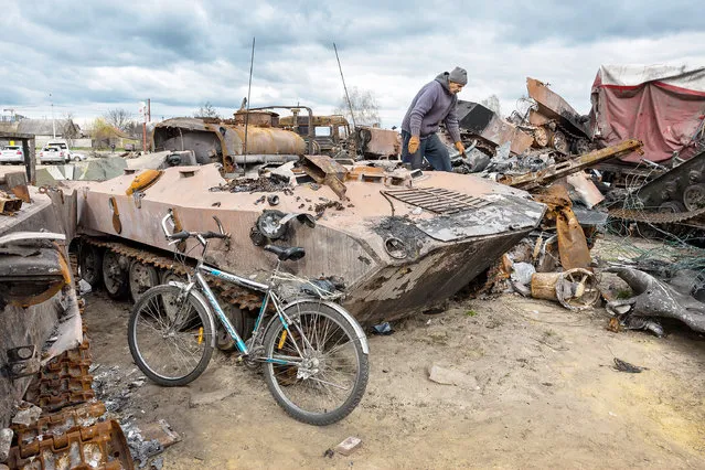 Local resident, Vladimir, 70, inspects destroyed Russian military vehicles on April 18, 2022 in Bucha, Ukraine. He, his disabled wife and adult son had stayed in Bucha during the Russian occupation, hiding in their basement. The Kyiv suburb was heavily damaged in fighting between invading Russian forces and Ukrainian troops weeks before. (Photo by John Moore/Getty Images)