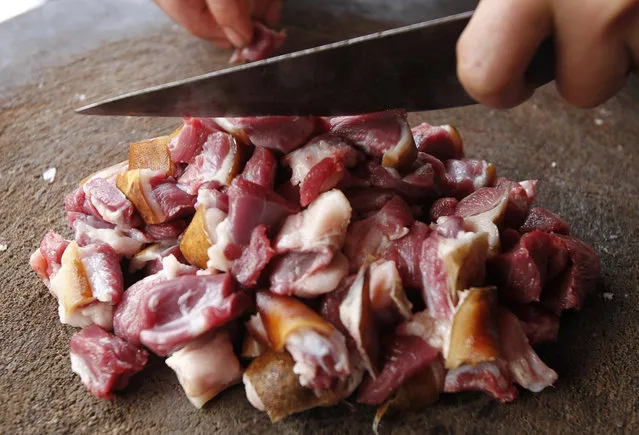 A vendor cuts dog meat for sale at his roadside stall in Duong Noi village, outside Hanoi December 16, 2011. While animal rights activists have condemned eating dog meat as cruel treatment of the animals, it is still an accepted popular delicacy for some Vietnamese, as well in some other Asian countries. Duong Noi is well-known as a dog-meat village, where hundreds of dogs are killed each day for sale as popular traditional food. Dog-eating as a custom is rooted in Vietnam and was developed as a result of poverty. One kilogram of dog meat costs about 130,000 dongs ($6.2). (Photo by Reuters/Kham)