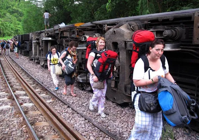 Passengers carry their belonging as they leave form a derailed train in Phrae province, northern Thailand Wednesday, July 17, 2013. The passenger train derailed on old tracks in the mountains of northern Thailand early Wednesday, slightly injuring at least 30 passengers, mostly foreign tourists. It was the second derailment on the popular route in a month. (Photo by AP Photo/Daily News)