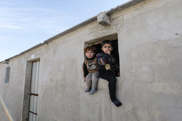 Children sit in a window of a new housing unit at a newly-constructed cement camp funded by an international charity, sheltering Syrians displaced by conflict in the village of Niyarah in the rebel-controlled northern countryside of Syria's Aleppo province near the Turkish border, on February 2, 2021. The new camp replaces an older one of tents, composed of hundreds of 35-square-metre housing units each equipped with two separate rooms, water cisterns, bathrooms and sewage systems, and solar panels. (Photo by Bakr Alkasem/AFP Photo)