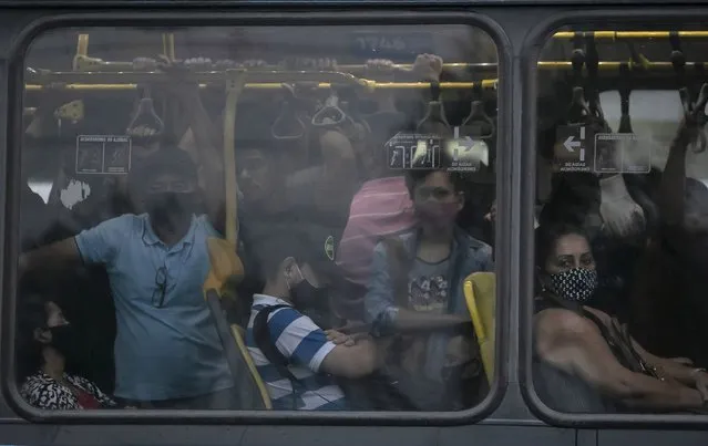 Commuters wearing masks due to the COVID-19 pandemic crowd a public Rapid Transit Bus (BRT) in Rio de Janeiro, Brazil, Tuesday, March 30, 2021. (Photo by Bruna Prado/AP Photo)