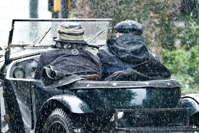 People in a soft-top vintage car get caught out in heavy rain showers while driving in the regatta town of Henley-on-Thames in Oxfordshire, United Kingdom on July 23, 2023. (Photo by Geoffrey Swaine/Rex Features/Shutterstock)