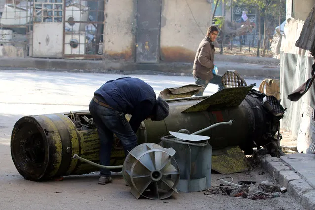 A man inspects an unexploded missile in the rebel-held besieged al-Qaterji neighbourhood of Aleppo, Syria November 28, 2016. (Photo by Abdalrhman Ismail/Reuters)