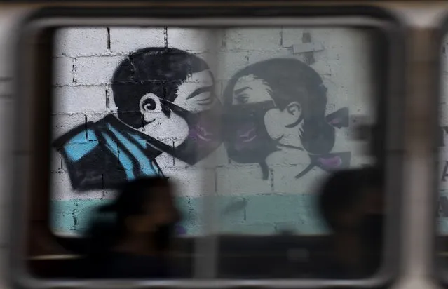 A bus passes a mural of a couple kissing while wearing face masks in Caracas, Venezuela, Wednesday, March 24, 2021, amid the new coronavirus pandemic. (Photo by Ariana Cubillos/AP Photo)