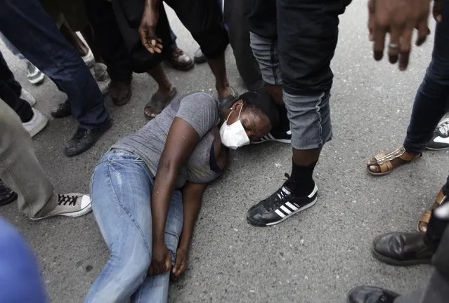 A woman lies on the floor, saying she was hit by a tear gas canister in her leg, during clashes with the police near Champs de Mars in Port-au-Prince February 13, 2015. (Photo by Andres Martinez Casares/Reuters)