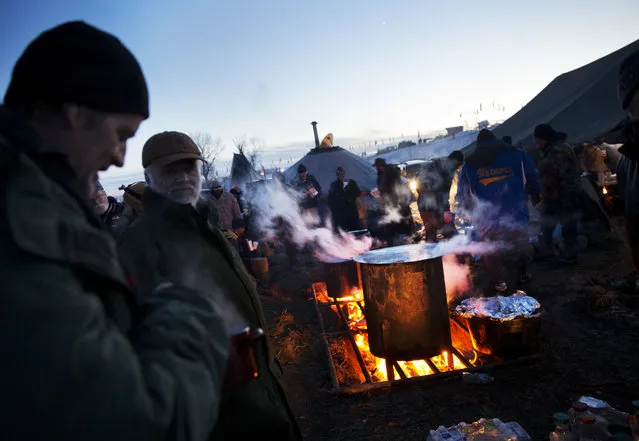 Veterans line up for dinner at the Oceti Sakowin camp where people have gathered to protest the Dakota Access oil pipeline in Cannon Ball, N.D., Sunday, December 4, 2016. The U.S. Army Corps of Engineers said Sunday afternoon that the four-state, $3.8 billion Dakota Access oil pipeline cannot be built under Lake Oahe, a Missouri River reservoir where construction had been on hold. (Photo by David Goldman/AP Photo)