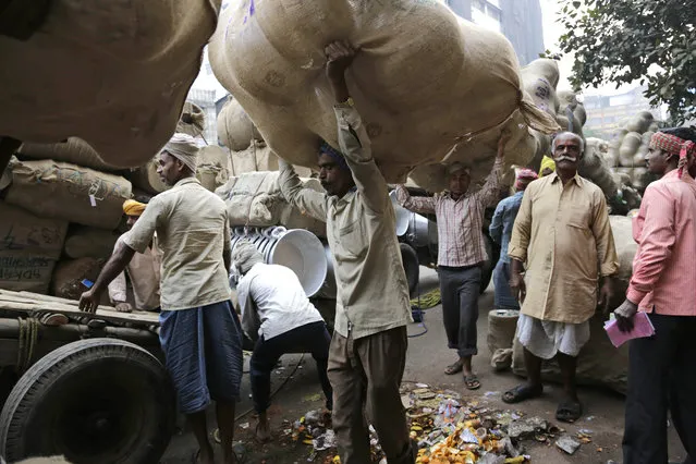 Indian laborers carry aluminum utensils to a warehouse at a wholesale market in Kolkata, India, Tuesday, February 10, 2015. Most laborers here, who are migrants from the neighboring states of Bihar and Jharkhand, live on the city's crowded pavements. (Photo by Bikas Das/AP Photo)