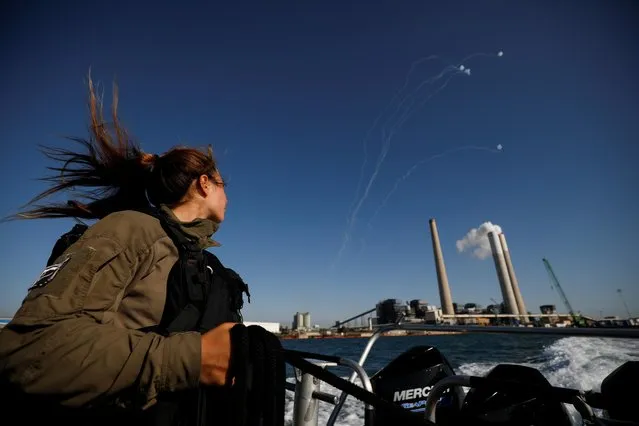 An Israeli soldier looks on as Israel's Iron Dome anti-missile system intercept rockets launched from the Gaza Strip towards Israel, as it seen from a naval boat patrolling the Mediterranean Sea off the southern Israeli coast as Israel-Gaza fighting rages on May 19, 2021. (Photo by Amir Cohen/Reuters)