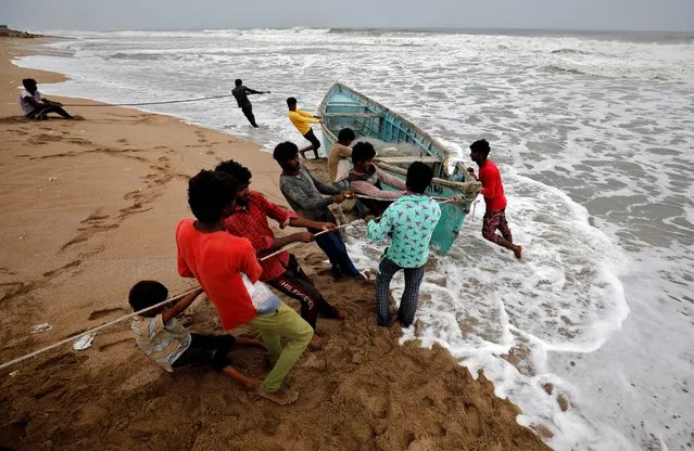 People move a fishing boat to a safer place along the shore ahead of Cyclone Tauktae in Veraval in the western state of Gujarat, India, May 17, 2021. (Photo by Amit Dave/Reuters)