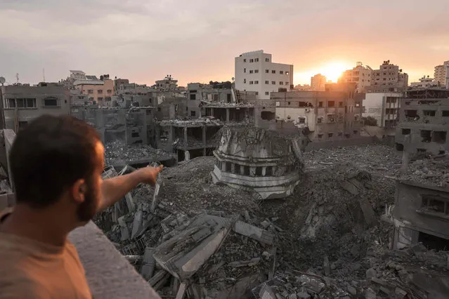 A Palestinian points to the Ahmed Yassin mosque, which was levelled by Israeli airstrikes, in Gaza City early on October 9, 2023. Israel relentlessly pounded the Gaza Strip overnight and into October 9 as fighting with Hamas continued around the Gaza Strip, as the death toll from the war against the Palestinian militants surged above 1,100. (Photo by Mohammed Abed/AFP Photo)