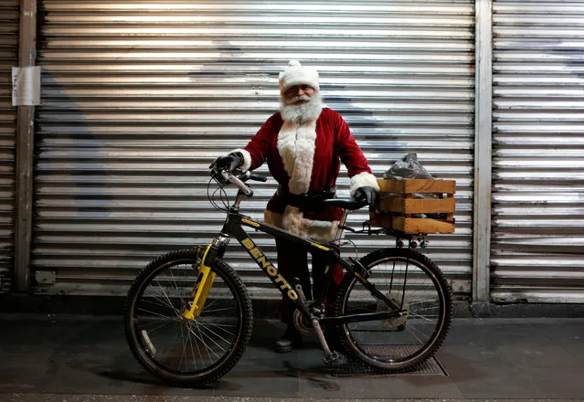 A man dressed as Santa Claus poses with his bicycle near Zocalo Square as part of Christmas celebrations in Mexico City, Mexico December 22, 2016. (Photo by Henry Romero/Reuters)