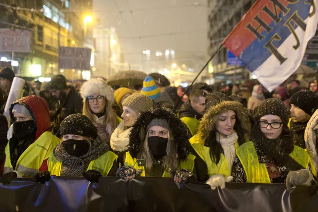 Protesters are seen on a snowy street in central Belgrade, Serbia, Saturday, December 15, 2018. Braving snow and cold weather, thousands marched in Serbia's capital in an outpouring of discontent with the autocratic rule of president Aleksandar Vucic and his government. (Photo by Marko Drobnjakovic/AP Photo)