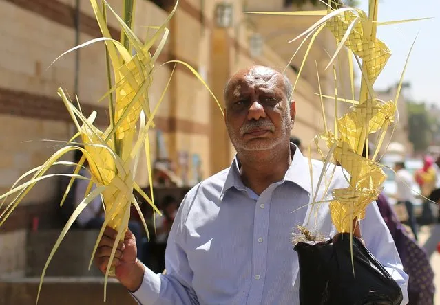 An Egyptian Coptic Christian man carries palm decorations during Palm Sunday as he waits outside a Church in Old Cairo, April 5, 2015. (Photo by Asmaa Waguih/Reuters)