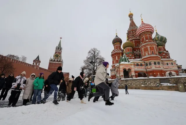 People walk across a snowbank near the Kremlin wall and St. Basil's Cathedral following a heavy snowfall in Moscow, Russia on November 27, 2023. (Photo by Evgenia Novozhenina/Reuters)