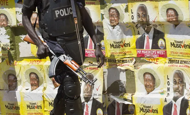 An armed Ugandan riot policeman patrols past campaign posters for long-time President Yoweri Museveni, as well as local members of Parliament, on a street in Kampala, Uganda Wednesday, February 17, 2016. (Photo by Ben Curtis/AP Photo)