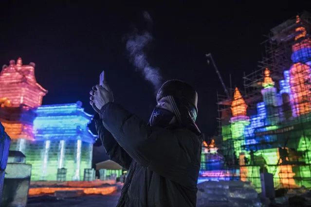 A Chinese worker takes a picture with his phone of ice sculptures he and others built in preparation for the Harbin Ice and Snow Festival on December 19, 2018 in Harbin, China. The annual winter festival, considered the worlds largest, officially opens January 5th, 2019, and runs for one month. The massive and detailed snow sculptures and full-sized illuminated ice buildings attract over a million visitors a year to the north-eastern city of Harbin, where the cold Siberian wind plunges the average temperature to -13 degrees Fahrenheit (-25 degrees Celcius). The elaborate ice buildings and intricately carved sculptures are made from blocks cut from the frozen Songhua River. For weeks before the festival, hired workers collect and transport nearly 200,000 cubic metres of ice to the site. Most of the cutters are farmers from nearby villages who start work before dawn at bitterly low temperatures to earn about $35 US per day. Blocks weighing up to 700 kilograms each are sculpted to different themes recreating animals and architectural wonders. Multi-colored lights give the structures a dazzling glow across the 750,000 square metre festival, which is marking its 35th year. (Photo by Kevin Frayer/Getty Images)