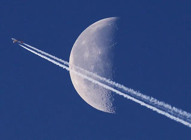 An aircraft leaves a trail in the sky as it passes the moon over Frankfurt, Germany, Friday, January 20, 2017. (Photo by Michael Probst/AP Photo)