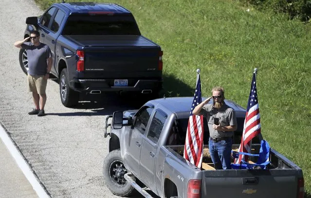 Two men pull off to the side of Interstate 70 westbound in St. Charles, Mo., to stand and salute as the convoy carrying the body of Marine Lance Cpl. Jared Schmitz passes by them on Wednesday, September 8, 2021. Thousands of people lined the highway and overpasses on Interstate 70 westbound as Schmitz's body was brought from St. Louis Lambert International Airport to Baue Funeral Home. Schmitz was one of 13 U.S. service members killed last month in a suicide bombing at the Kabul airport in Afghanistan. (Photo by David Carson/St. Louis Post-Dispatch via AP Photo)
