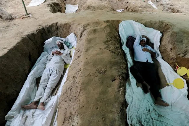 Farmers lie in graves which they dug as part of protests against the farms laws, at Mandola village in Ghaziabad, India, September 21, 2021. (Photo by Anushree Fadnavis/Reuters)