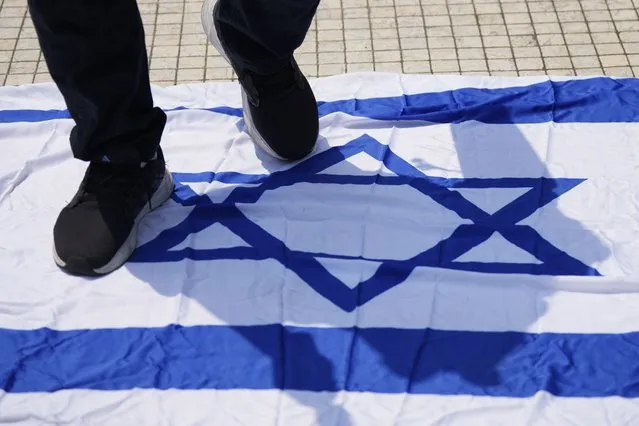 A man steps on an Israeli flag during a protest outside national mosque after the Friday prayer in Kuala Lumpur, Malaysia, Friday, October 13, 2023. (Photo by Vincent Thian/AP Photo)