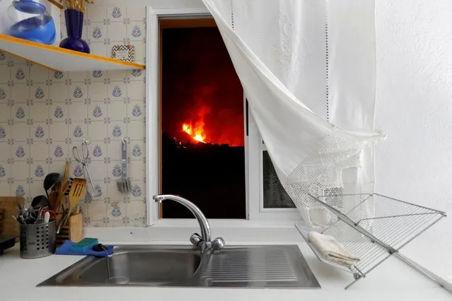 Lava is seen through the window of a kitchen from El Paso following the eruption of a volcano on the Canary Island of La Palma, Spain, September 28, 2021. (Photo by Jon Nazca/Reuters)