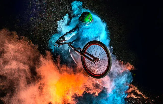 The biker with the holi powder behind whilst performing stunts. (Photo by Christoph Jorda/Caters News)