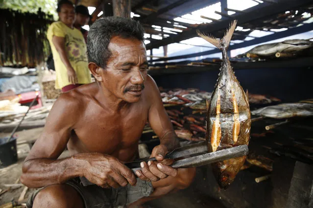 A worker shows his grilled fish during processing on Maitara island before selling it at the local Tidore market in North Maluku province, Indonesia, March 11, 2016. (Photo by Reuters/Beawiharta)