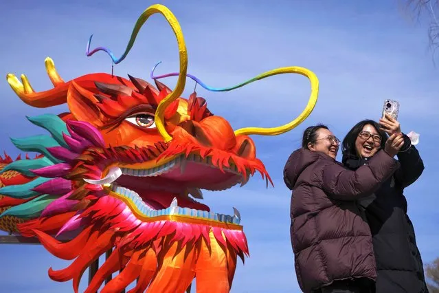 Women take a selfie with a giant dragon lantern decorated near the frozen Houhai Lake in Beijing, Thursday, February 8, 2024. (Photo by Andy Wong/AP Photo)