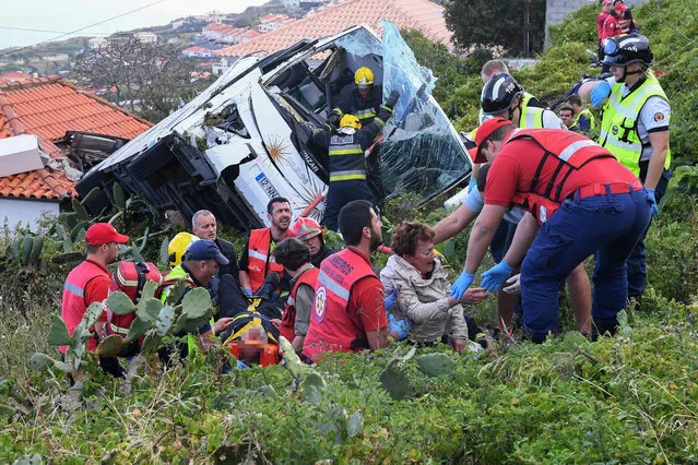 Firemen help victims of a tourist bus that crashed on April 17, 2019 in Caniço, on the Portuguese island of Madeira. At least 28 people were killed when a tourist bus crashed on the Portuguese island of Madeira, the local mayor told local media. The regional protection service did not confirm the toll when questioned by AFP. (Photo by Rui Silva/AFP Photo)
