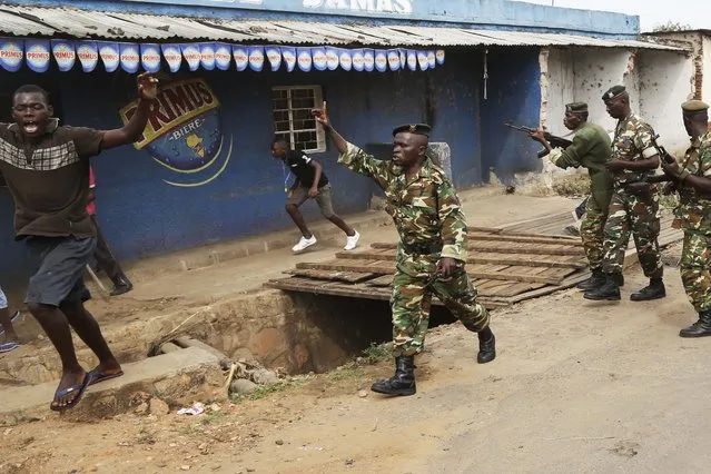 Demonstrators duck and run from soldiers firing into the air to disperse a crowd of demonstrators who had cornered  Jean Claude Niyonzima a suspected member of the ruling party's Imbonerakure youth militia in a sewer in the Cibitoke district of Bujumbura, Burundi, Thursday May 7, 2015. (Photo by Jerome Delay/AP Photo)