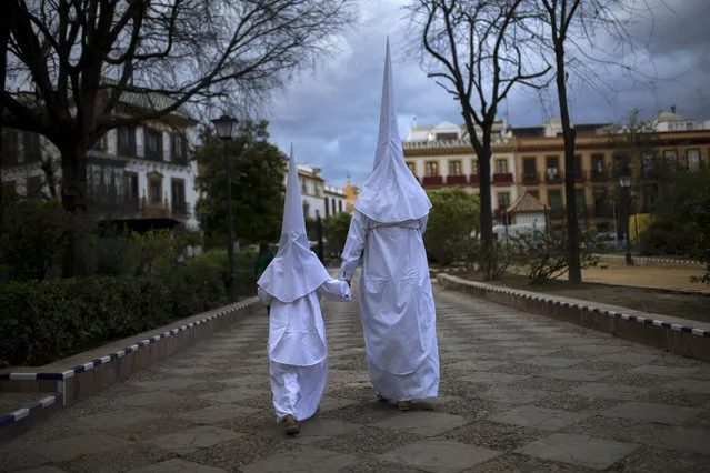Hooded penitents from the “La Candelaria” brotherhood walk to the church to take part in a traditional annual procession in Seville, Spain, Tuesday, March 22, 2016. (Photo by Francisco Seco/AP Photo)