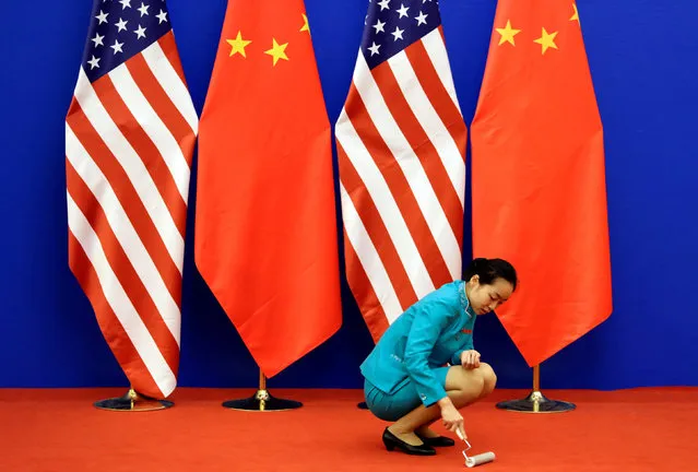 An attendant cleans the carpet next to U.S. and Chinese national flags before a news conference for the 6th round of U.S.-China Strategic and Economic Dialogue at the Great Hall of the People in Beijing, July 10, 2014. (Photo by Jason Lee/Reuters)