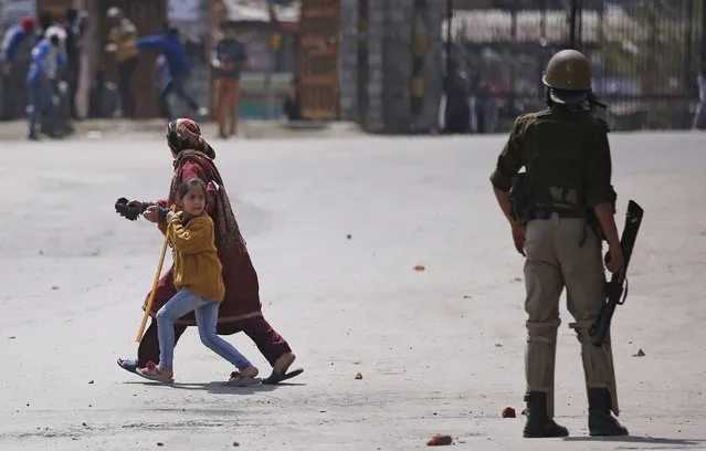 A Kashmiri woman and her daughter run past a policeman to safety as protesters (unseen) hurl stones towards police during a protest in Srinagar April 8, 2016. The demonstrators held the protest after Friday prayers demanding what they said was freedom from Indian rule in Kashmir. (Photo by Danish Siddiqui/Reuters)