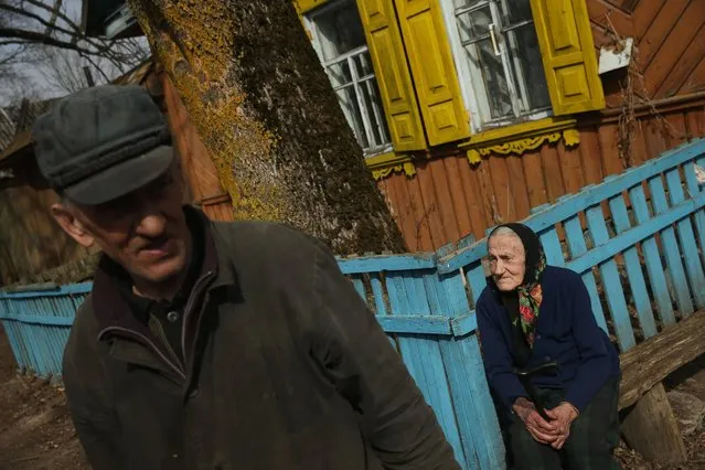 Yelyena Muzichenka, 86, and Nilokai Gardunov, 62, are seen outside Yelyena's house, April 6, 2016, in Bartolomeyevka, Belarus. Today, only four residents live in Bartolomeyevka, a former village located in southeastern Belarus that was contaminated after the explosion at the Chernobyl nuclear power plant. (Photo by Sean Gallup/Getty Images)