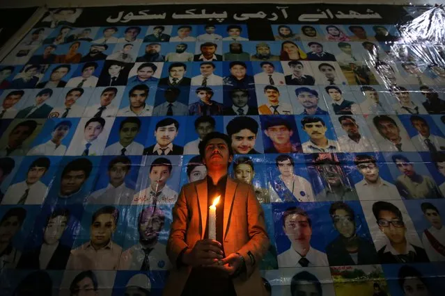A man hold candle front of the portraits of victims during a memorial ceremony for the victims of Army Public School (APS) attack on the seventh anniversary of the Peshawar school attack, in Peshawar, Pakistan, 16 December 2021. In December 2014 Taliban militants attacked the army-run Army Public School in the north-western city of Peshawar, where about 150 people, mostly students, were killed. (Photo by Bilawal Arbab/EPA/EFE)