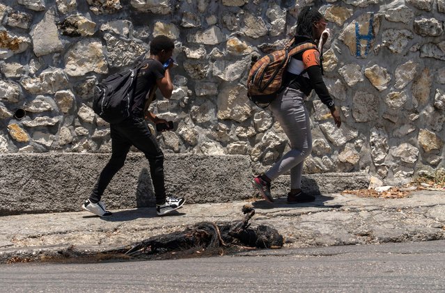 Pedestrians walk past a charred body in Port-au-Prince's Petion-Ville neighborhood, Haiti, Sunday, April 21, 2024. (Photo by Ramon Espinosa/AP Photo)