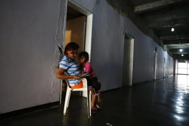 Beatriz fills out a crossword while taking care of her grandchildren outside their apartment, inside of the “Tower of David” skyscraper in Caracas February 3, 2014. (Photo by Jorge Silva/Reuters)