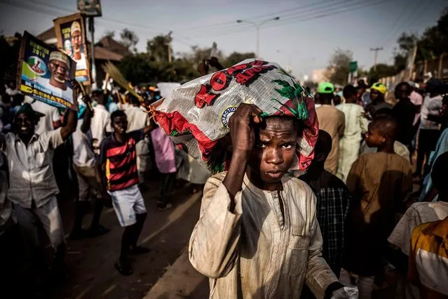 A boy cover himself with a plastic bag while All Progressives Congress Party (APC) supporters celebrate initial results released by the Nigerian Independent National Electoral Commission (INEC) in Kano, on February 25, 2019, two days after general elections. (Photo by Luis Tato/AFP Photo)