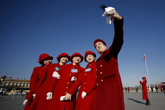 In this Sunday, March 5, 2017 photo, hospitality staff take selfies on Tiananmen Square during the National People's Congress held at the Great Hall of the People in Beijing. (Photo by Andy Wong/AP Photo)