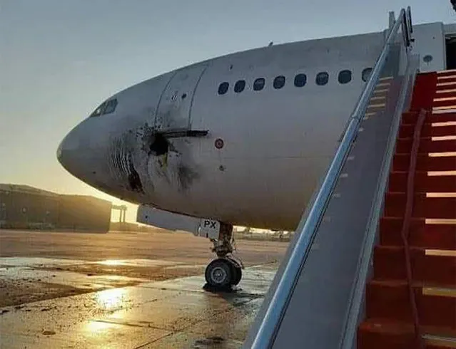 A handout picture released by the Facebook page of the Iraqi ministry of transportation, shows a damaged stationary aircraft on the tarmac of Baghdad airport, after rockets reportedly tragetted the runway, on January 28, 2022. Six rockets were fired at the Iraqi capital's airport at dawn today, causing damage to a plane but no casualties, two security sources said. (Photo by Facebook Page of the Iraqi Ministry of Transportation/AFP Photo)