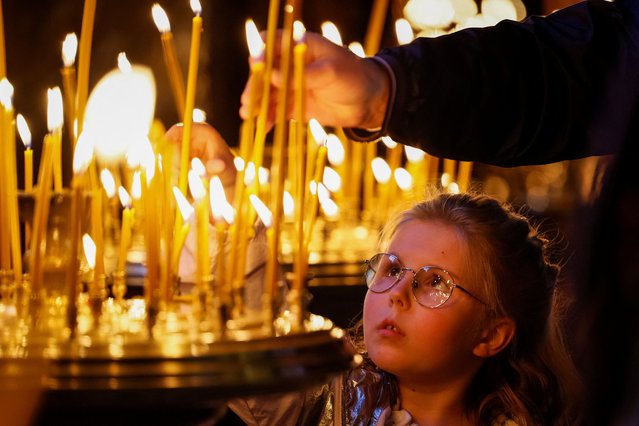 A girl lights a candle during an Easter service in the Volodymyrsky Cathedral, amid Russia's attack on Ukraine, in Kyiv, Ukraine, on May 4, 2024. (Photo by Alina Smutko/Reuters)