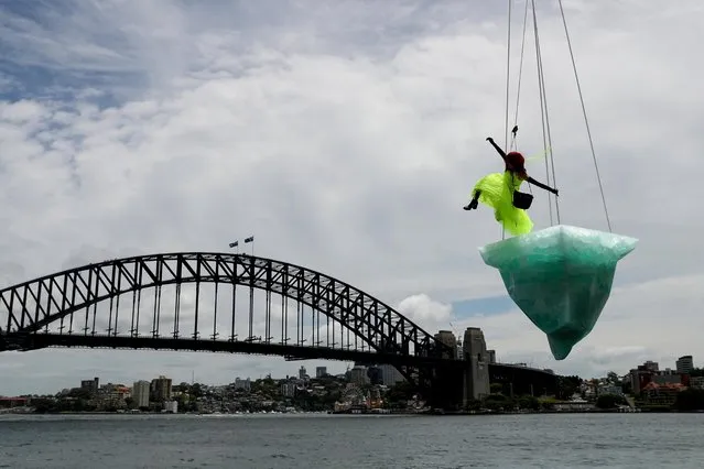 Vicki Van Hout performs atop a 2.7 tonne iceberg suspended above Sydney Harbour during the opening show of the Sydney Festival production ​Thaw, in Sydney, Australia, 14 January 2022. (Photo by Brendon Thorne/EPA/EFE)