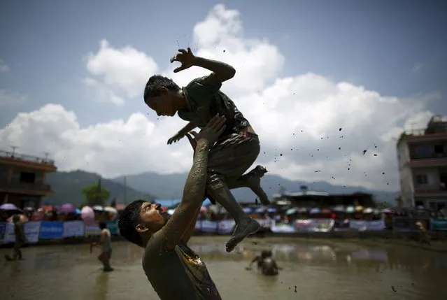A man carries a boy as they play in the mud during the Asar Pandhra festival in Pokhara valley, west of Nepal's capital Kathmandu, June 30, 2015. (Photo by Navesh Chitrakar/Reuters)