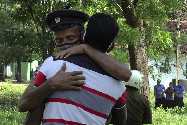 A Sri Lankan police officer, facing camera, hugs to console a relative of a victim at a police station in Thirukkovil, Sri Lanka, Saturday, December 25, 2021. A policeman has opened fire on a group of fellow officers in Sri Lanka, killing four of them and wounding three others. The shooting occurred Friday night inside a police station in the small town of Thirukkovil in eastern Sri Lanka, a police statement said. (Photo by Achala Pussalla/AP Photo)