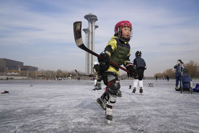 A child practices ice hockey near the Beijing Olympics Tower in Beijing, China, Tuesday, January 18, 2022. The Beijing Winter Olympics is tapping into and encouraging growing interest among Chinese in skiing, skating, hockey and other previously unfamiliar winter sports. It's also creating new business opportunities. (Photo by Ng Han Guan/AP Photo)